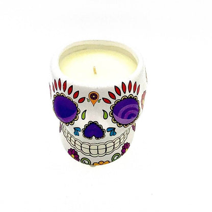 The Small White Ceramic Skull Candle – Nutmeg Scented features a skull-shaped container with colorful Day of the Dead-inspired patterns, making this soy wax candle a vibrant accent against any simple white backdrop.