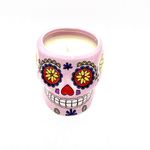 The Large Pink Ceramic Skull Candle is made with white soy wax and features a vibrant Day of the Dead sugar skull design with colorful floral patterns. Scented with nutmeg, it comes in a decorative pink ceramic holder.