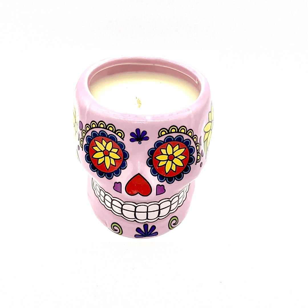 The Large Pink Ceramic Skull Candle is made with white soy wax and features a vibrant Day of the Dead sugar skull design with colorful floral patterns. Scented with nutmeg, it comes in a decorative pink ceramic holder.