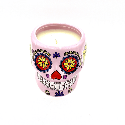 The Large Pink Ceramic Skull Candle is made with white soy wax and features a vibrant Day of the Dead sugar skull design with colorful floral patterns. Scented with nutmeg, it comes in a decorative pink ceramic holder.