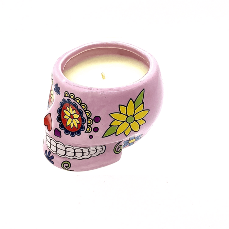 The Large Pink Ceramic Skull Candle features colorful floral designs and is filled with white nutmeg-scented soy wax, shown on a white background.