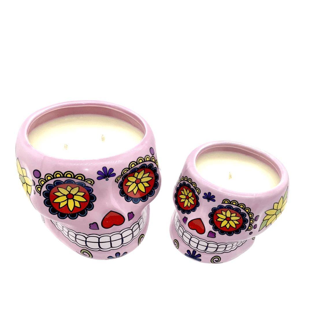 Two Large Pink Ceramic Skull Candles, nutmeg scented, in festive sugar skull containers with colorful floral and heart designs—perfect for adding warm glow and charm to any space.