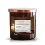 The Musical Spa Cashmere Candle, in a brown glass jar with metallic lid, offers relaxing linen, saffron, vanilla, and patchouli notes for a soothing spa experience.