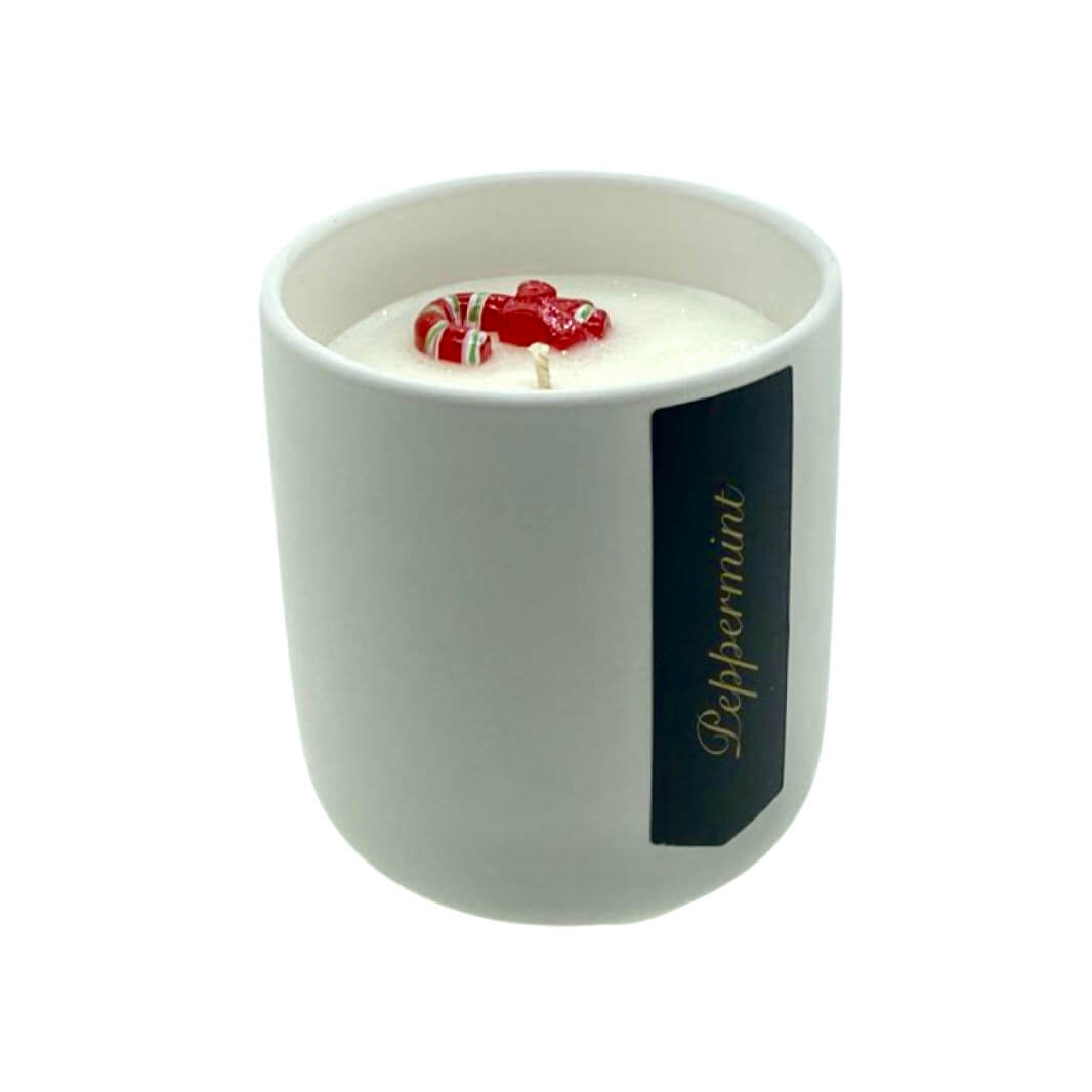 The Holiday Scented Boxed Candle – Peppermint Scent features a refreshing peppermint aroma in a white container, topped with candy cane and mitten shapes, and is crafted from natural soy wax.