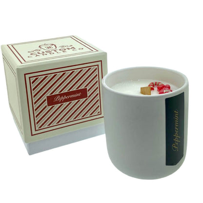 The Holiday Scented Boxed Candle – Peppermint Scent, made from natural soy wax and topped with peppermint pieces, comes in a white ceramic jar and is paired with a matching red and cream striped box.