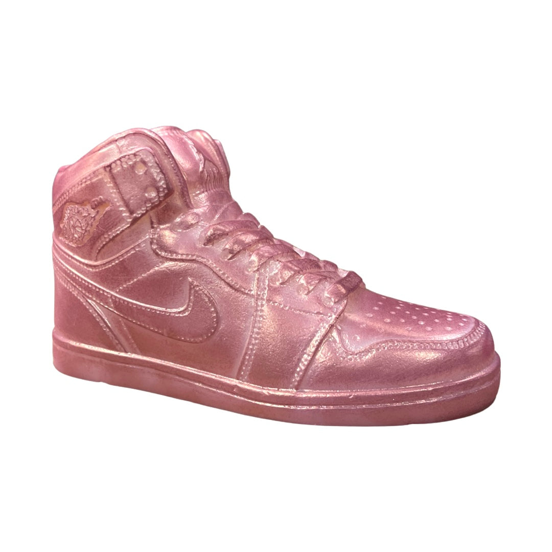 The AJ-1 Pink Shimmer Sneaker Candle (On Backorder) is a pink, high-top sneaker-shaped candle, hand poured from all-natural wax with a glossy finish and styled to resemble a Nike Air Jordan, shown against a white background.