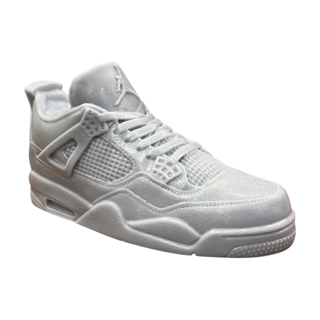 The AJ-4 Gray Sneaker Candle – XL (On Backorder) is a monochromatic light gray candle, styled after the Air Jordan 4, shown in profile on a white background, hand poured with a subtle Black Ice scent.