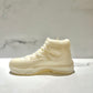 The AJ-11 White Hightop Sneaker Candle – Large (On Backorder), hand poured and infused with Black Ice fragrance, rests on a white surface against a light marble background.