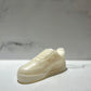 The AF1 – White Lowtop Sneaker Candle – Large (On Backorder), shaped like a white sneaker and possibly featuring a hint of Black Ice fragrance, is displayed on a white surface against a plain background.