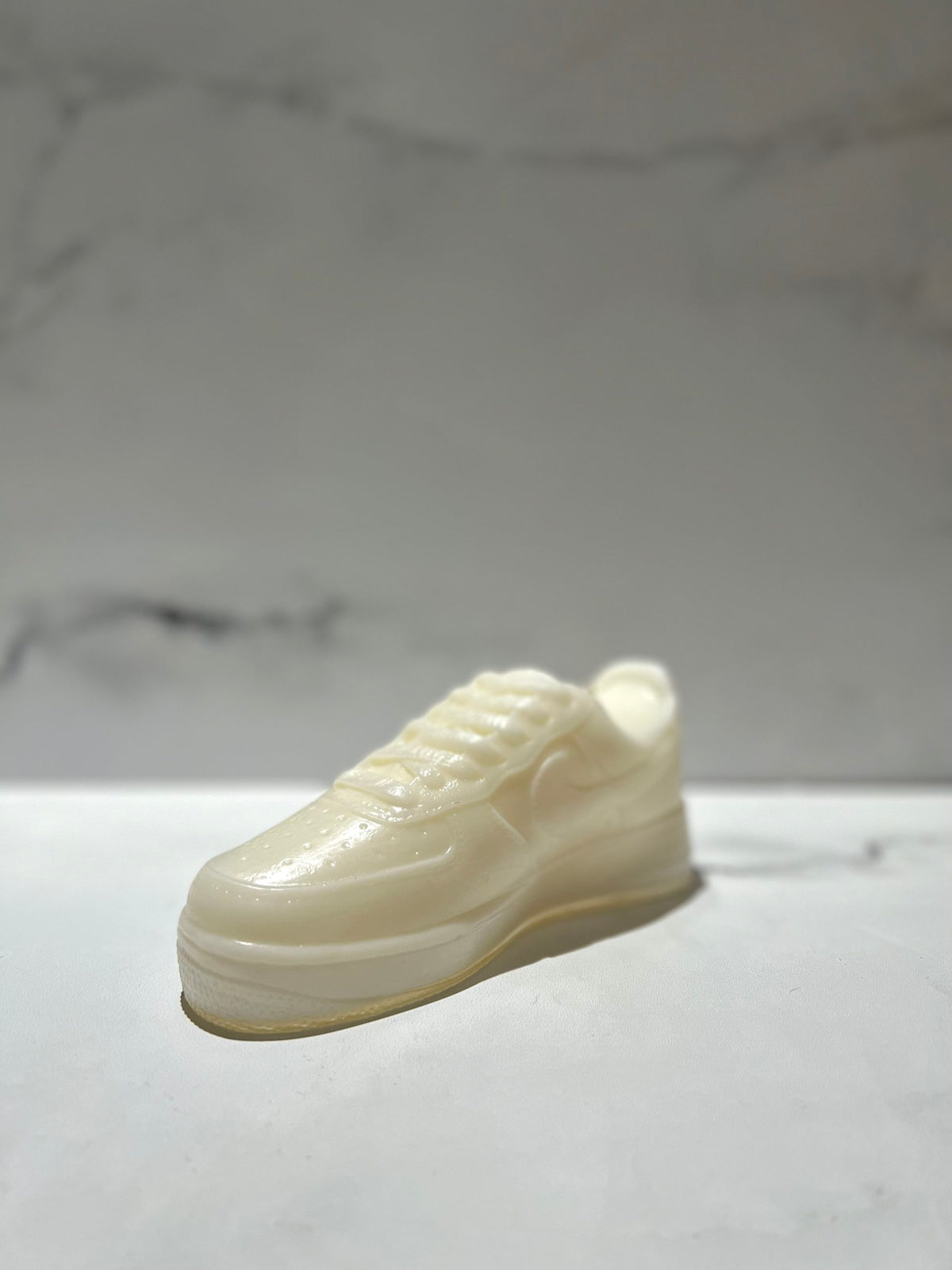 The AF1 – White Lowtop Sneaker Candle – Large (On Backorder), shaped like a white sneaker and possibly featuring a hint of Black Ice fragrance, is displayed on a white surface against a plain background.