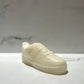 The AF1 – White Lowtop Sneaker Candle – Large (On Backorder), designed to resemble a classic white lowtop sneaker, rests on a light marble surface with a blurred marble-patterned background.