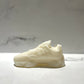 The Y500 – White Sneaker Candle – Large (On Backorder) is shown on a light marble surface with a blurred marble-patterned background, highlighting the distinct appeal of this hand-poured candle.