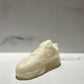 The Y500 – White Sneaker Candle – Large (On Backorder) is hand poured and shaped like a classic sneaker, displayed on a white surface with a blurred marble background.