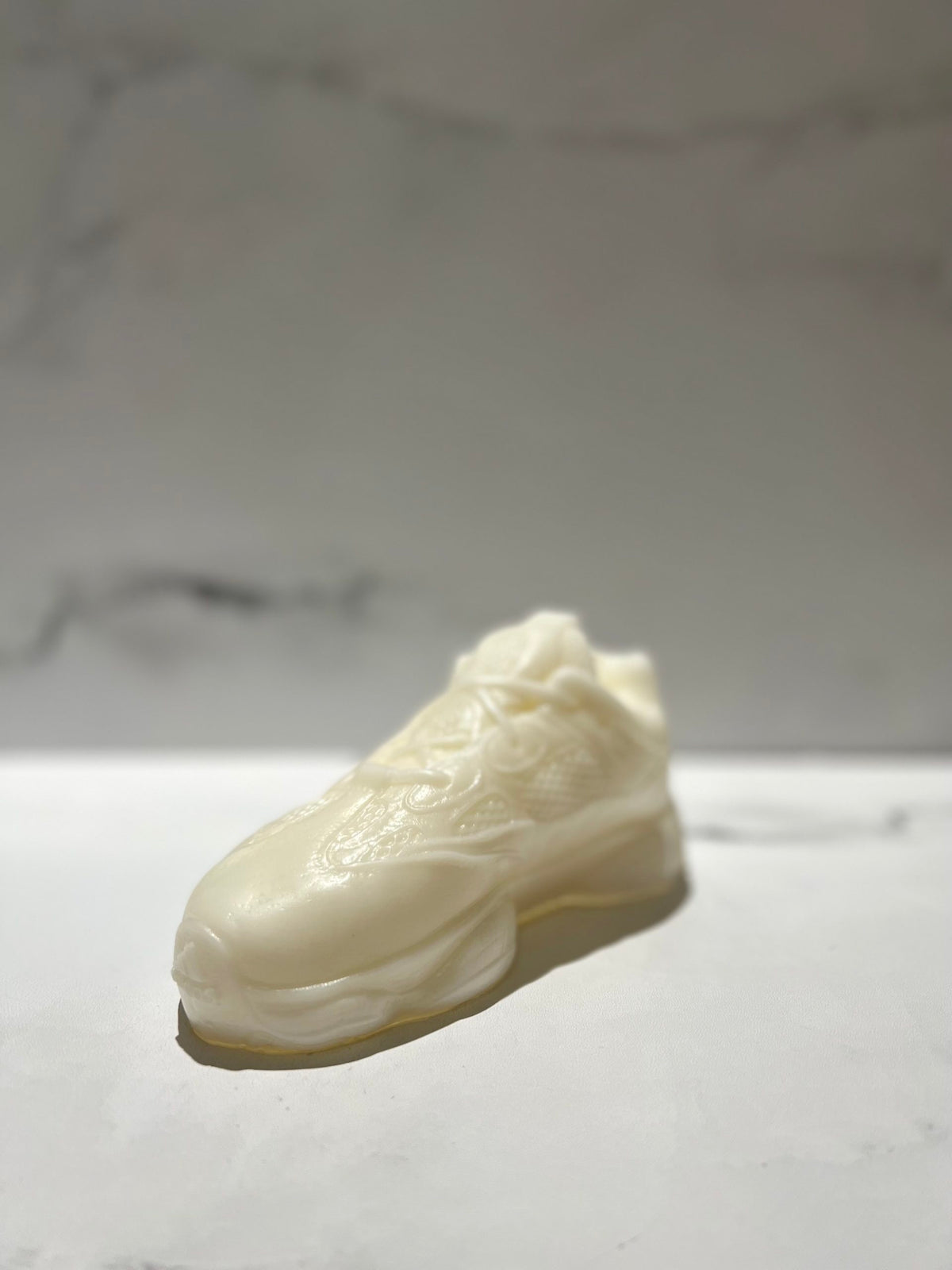 The Y500 – White Sneaker Candle – Small (currently on backorder) is a hand-poured, realistic white sneaker candle with a subtle Black Ice scent, displayed on a white surface against a soft gray backdrop.