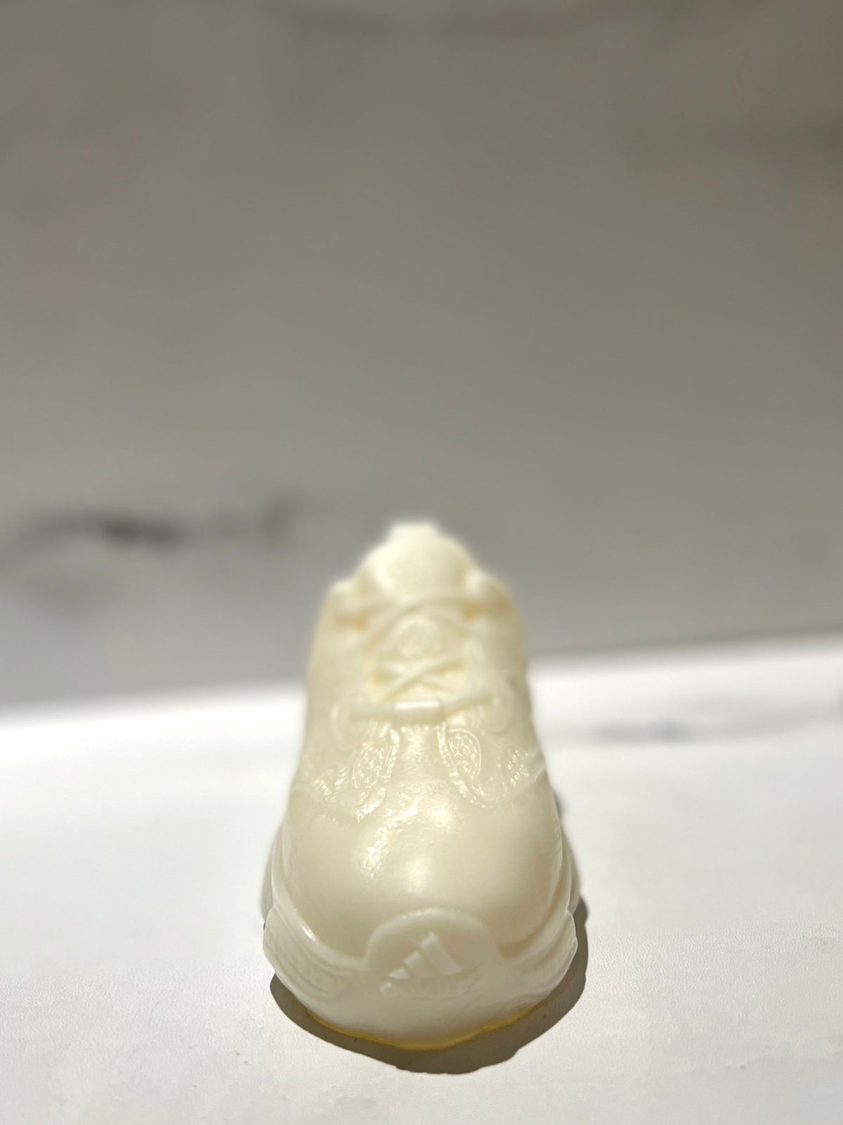 The Y500 – White Sneaker Candle – Large (On Backorder) is displayed on a white surface with a blurred background.