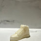 The AJ-1 White Hightop Sneaker Candle – Large (On Backorder) is a hand-poured candle shaped like a white high-top sneaker, set on a white surface with a marble background. It features subtle notes of Black Ice fragrance for a unique touch.
