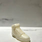 The AJ-1 White Hightop Sneaker Candle – Large (On Backorder) is a hand-poured candle shaped like a high-top sneaker, crafted from a smooth white material and displayed on a light surface with a blurred background.
