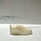The AF1 – White Lowtop Sneaker Candle – Small (On Backorder) features a fresh Black Ice scent and a unique white design, showcased on a marble surface with its details standing out against the soft, blurred background.