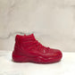The AJ-11 Red Hightop Sneaker Candle – Large (On Backorder), a hand-poured, all-natural wax candle in a red high-top sneaker design, is shown on a white marble surface with a light marble background.