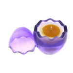 The Purple Glass Easter Egg w/ Yoke is an egg-shaped, purple candle holder with a removable lid, featuring a natural wax candle designed to resemble a cracked egg with a yellow yolk inside.