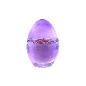 The Purple Glass Easter Egg w/ Yoke is a purple, translucent, egg-shaped candle featuring a wavy line around the middle and crafted from natural wax.