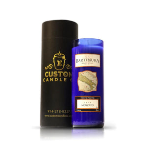A Recycled Dark Blue Italian Wine Candle, labeled "Bartenura Moscato," stands beside a sleek black "Custom Candle Co." container, highlighting the elegance of eco-friendly candles.