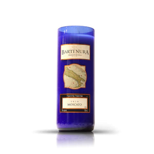 The Recycled Dark Blue Italian Wine Candle, made from an upcycled bottle with a "Bartenura Moscato" label and map graphic, stands upright against a white background—a distinctive eco-friendly candle option.