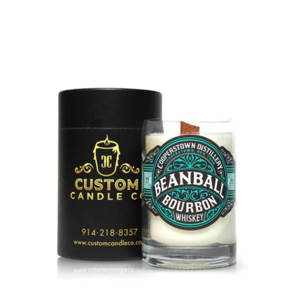 A white Recycled Bourbon Whiskey Candle in a glass made from upcycled whiskey bottles is shown beside a black and gold "Custom Candle Co." container.