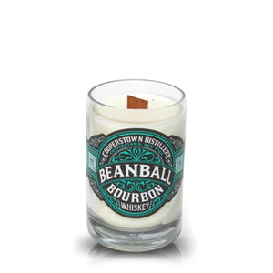 The Recycled Bourbon Whiskey Candle from Cooperstown Distillery is crafted from an upcycled whiskey bottle, features white wax, and includes a wooden wick.