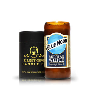 The Recycled Belgian White Beer Candle, a sustainable hand-poured candle made from a recycled Blue Moon Belgian White bottle, sits beside a black Custom Candle Co. container.