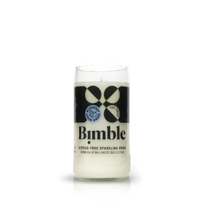 A clear glass labeled "Recycled Sparkling Water Candle" holds a white liquid. The label highlights 25mg THC for calm, balanced, delicious stress-free sipping—and the bottle is ideal for upcycling as a candle after you finish.