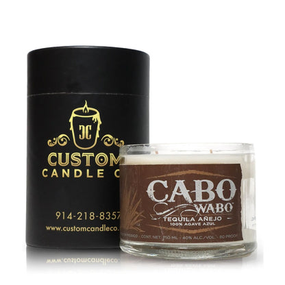 A Custom Candle Co. black cylindrical container sits next to a Recycled Azul Agave Anejo Tequila Candle, displayed in a glass bottle with brown and white design accents.