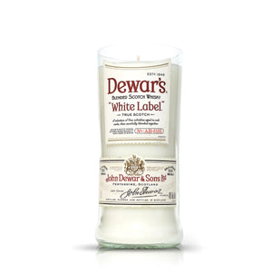 The Recycled White Label Scotch Whiskey Candle is a white candle in a glass vessel made from an upcycled Dewar’s White Label blended Scotch whisky bottle.
