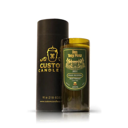 The Recycled Gran Reserva Wine Candle, crafted from recycled bottles and labeled "Don Tony Perez 2021 Gran Reserva Petit Verdot," stands beside its black cylindrical packaging, showcasing our eco-friendly approach.