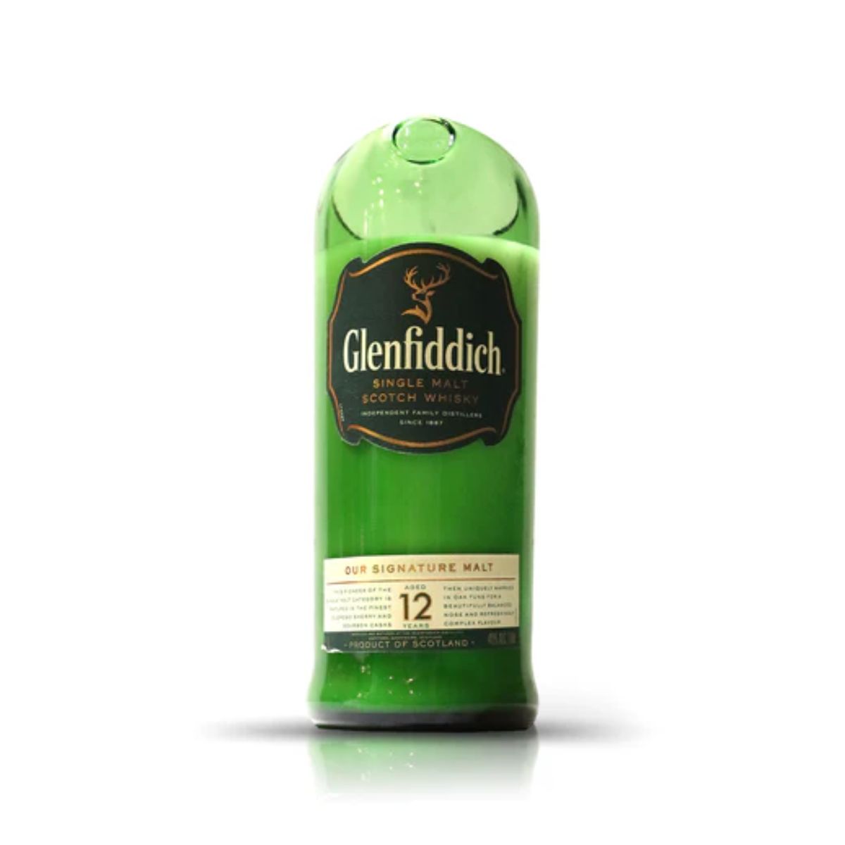A Recycled Green Scotch Whiskey Candle made from a partially melted Glenfiddich 12 Year Old bottle, label intact, stands on a white background.