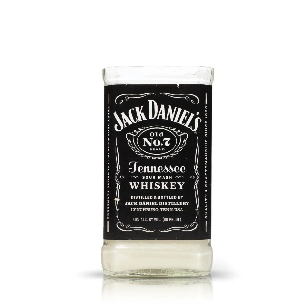 The Recycled Sour Mash Whiskey Candle is crafted from a clear glass featuring the iconic black-and-white Jack Daniel’s Old No. 7 label, upcycled into a candle with coconut-apricot wax and a small amount of liquid at the base.