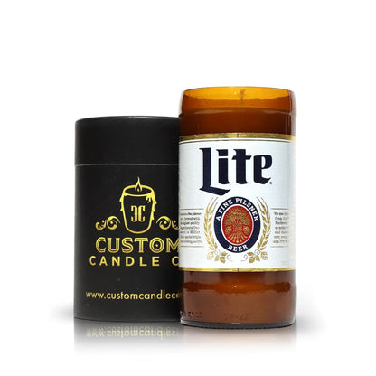 A Recycled Pilsner Beer Candle, hand poured in a repurposed Miller Lite bottle, sits next to a black Custom Candle Co. container with gold logo on a crisp white background.