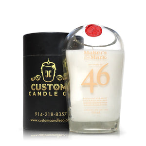 A Recycled 46# Straight Bourbon Whiskey Candle in an upcycled bottle sits beside its black cylindrical Custom Candle Co. packaging.