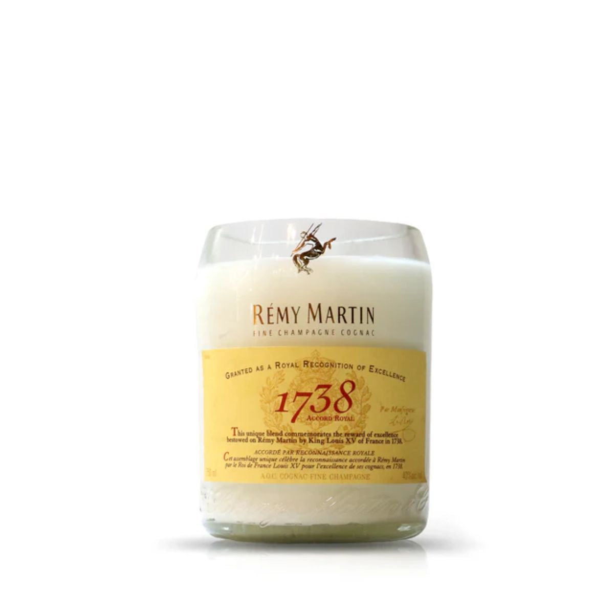 The Recycled Cognac Candle is a white candle in a glass container, made from recycled cognac bottles, and displays a Rémy Martin 1738 Accord Royal label on the front.