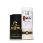 A Recycled Red Letter Vodka Candle sits beside a black cylindrical box labeled "Custom Candle Co."—an eco-friendly, artisanal candle repurposed from a vodka bottle for unique ambiance.