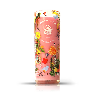 The Recycled Summer Pink Wine Candle is a tall upcycled bottle candle featuring a “Summer in a Bottle 2022 Long Island, NY” label with colorful floral and fruit designs on a pink background.