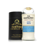 A Recycled Founder's Reserve Scotch Whiskey Candle, made in a repurposed Glenlivet bottle, sits beside a Custom Candle Co. branded cylindrical container.