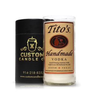 A Recycled Old Fashion Vodka Candle with a Tito's Handmade Vodka label stands beside a black Custom Candle Co. container, highlighting artisanal candles made from recycled bottles.