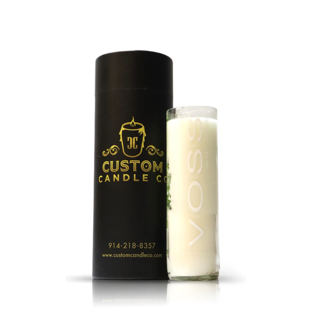 The Recycled Lime Mint Sparkling Water Candle, set in a clear upcycled Voss glass, sits beside a sleek black cylinder labeled "Custom Candle Co" with gold accents, making for chic home decor.