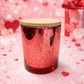 Red Mercury Glass Candle with a bamboo lid on a pink background with hearts and gift boxes