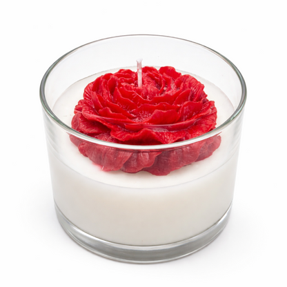 The Rose Blossom Candle is a handmade, all-natural soy candle in a glass container, featuring a white base topped with a decorative red wax rose.