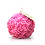 The Pink Pastel Rose Candle, featuring a round shape, pink hue, delicate rose pattern, and a small tag on the wick, is displayed against a white background.