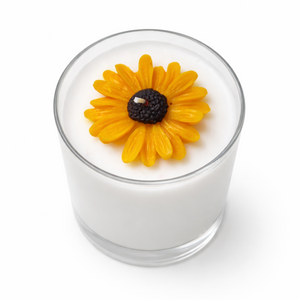 Candle with a yellow flower on top against a white background