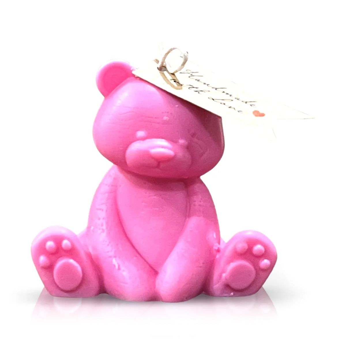 The Teddy Bear Pastel Pink Baby Candle is a small, pastel pink candle shaped like a teddy bear with outstretched arms and legs, featuring a tag on its ear and displayed on a white background.