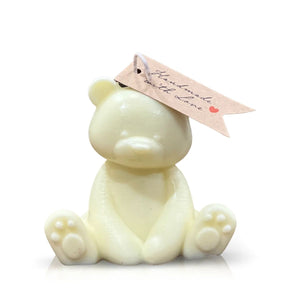The Teddy Bear Pastel Yellow Baby Candle sits upright with a brown tag reading "Handmade with Love" attached to its ear.